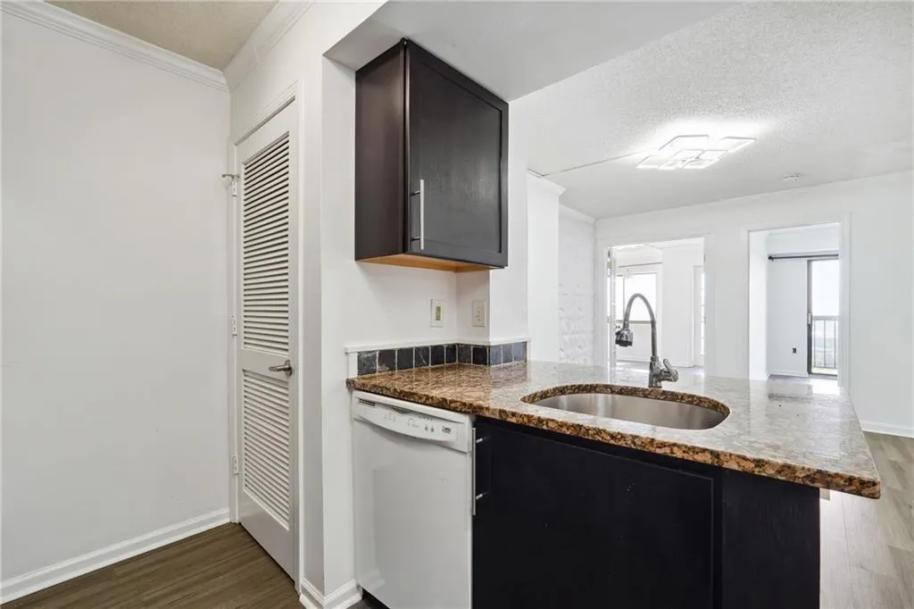 Kitchen featuring a textured ceiling, sink, hardwood / wood-style flooring, and dishwasher