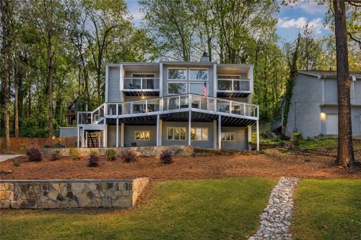 Multi-level exterior with extensive decking, integrated stone retaining wall, and landscaped terraced planting beds