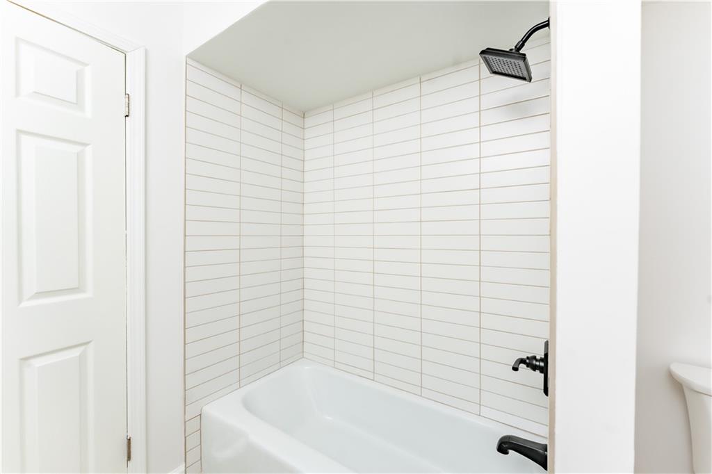 Bathroom with toilet and tiled shower / bath combo
