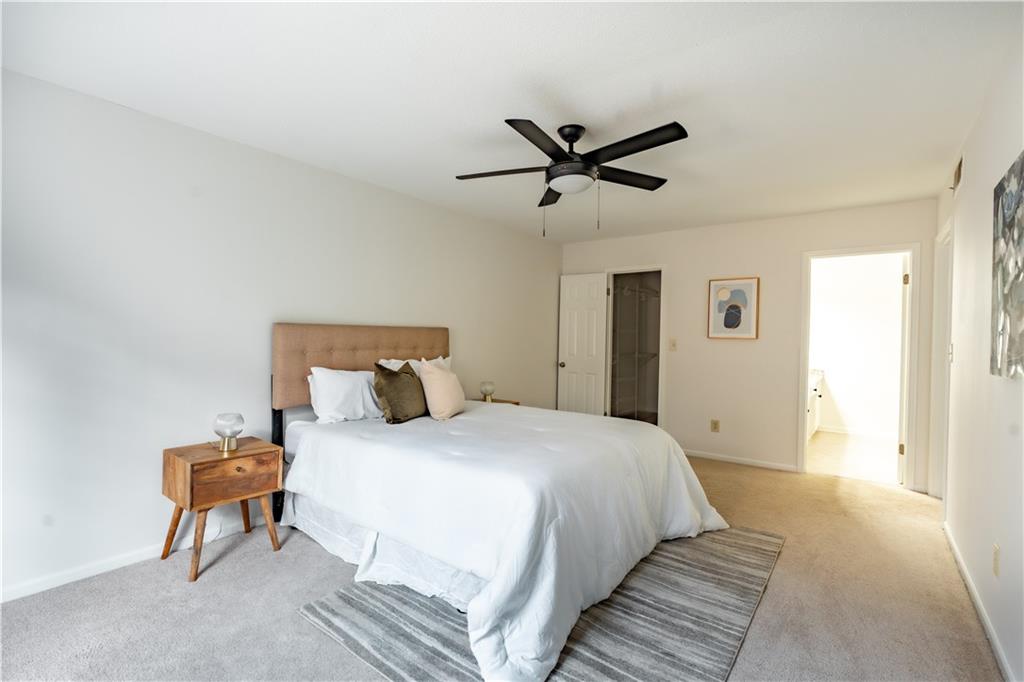 Bedroom with light carpet, ceiling fan, ensuite bathroom, and a closet
