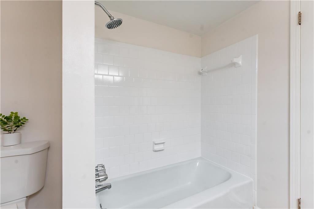 Bathroom with tiled shower / bath combo and toilet
