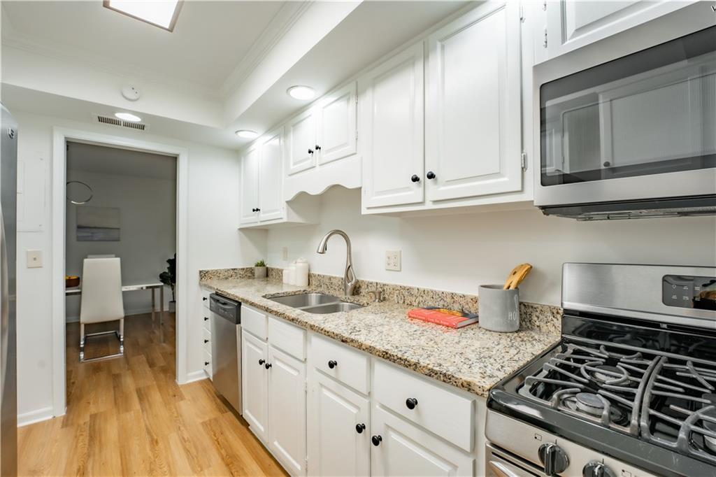 Kitchen featuring white cabinetry, appliances with stainless steel finishes, light hardwood / wood-style flooring, and sink