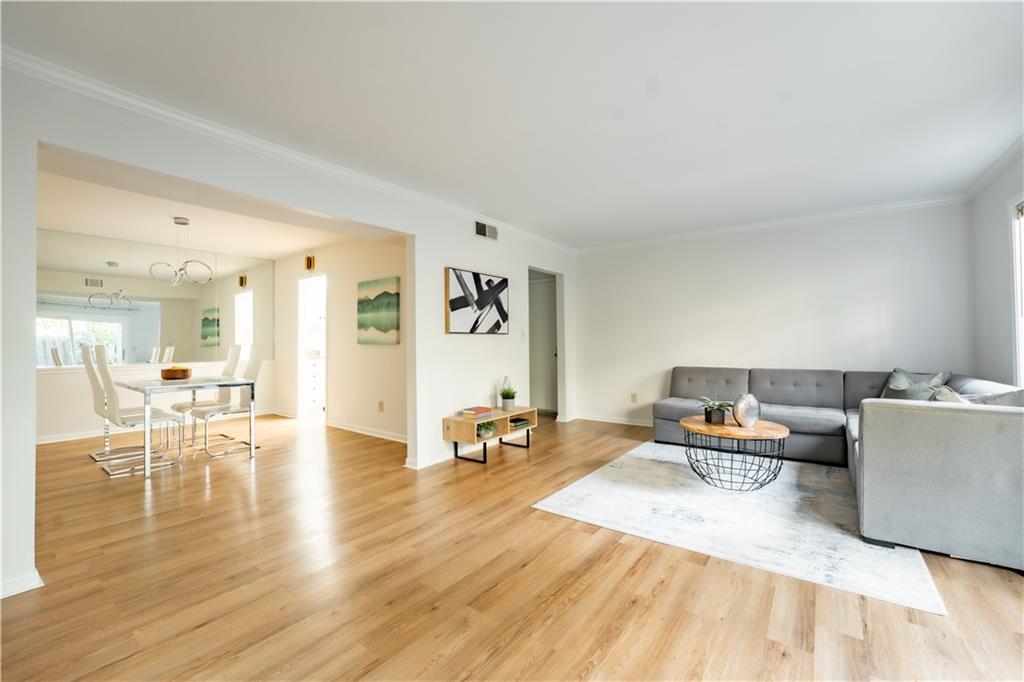 Living room with an inviting chandelier, light hardwood / wood-style flooring, and ornamental molding