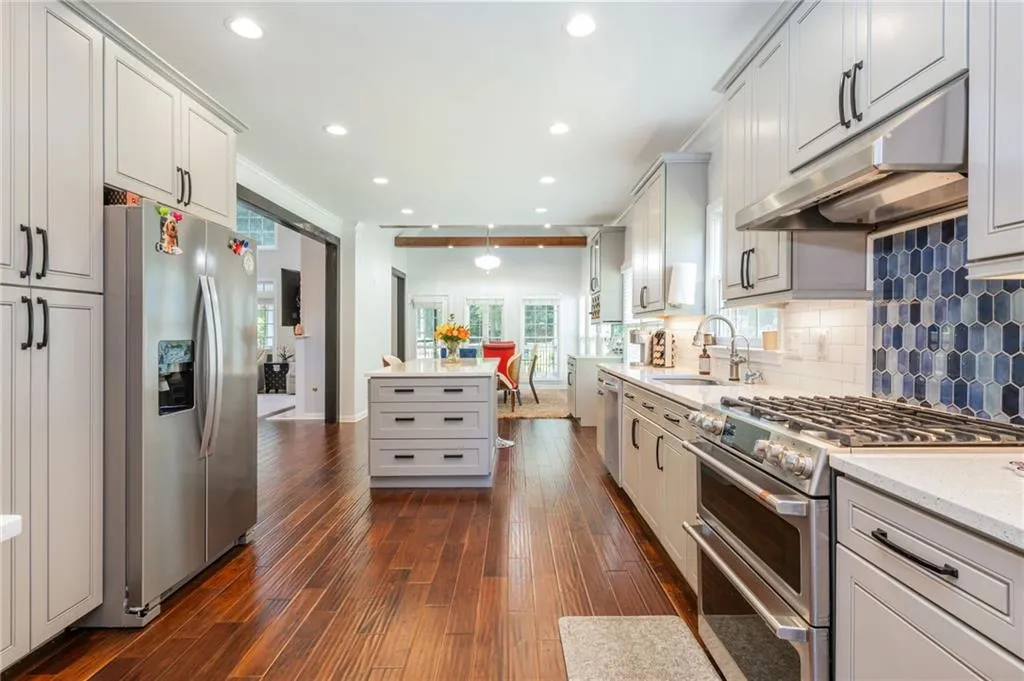 Kitchen featuring stainless steel appliances, under cabinet range hood, dark wood flooring, tasteful backsplash, and recessed lighting