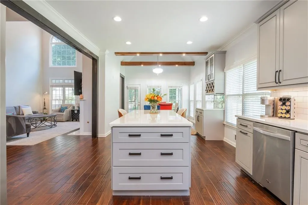 Kitchen featuring stainless steel dishwasher, gray cabinetry, ornamental molding, dark wood-type flooring, and light countertops