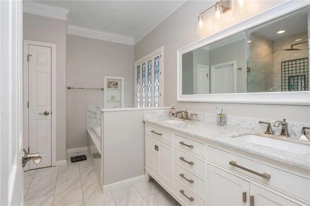 Full bath featuring double vanity, ornamental molding, a stall shower, a garden tub, and marble finish floors