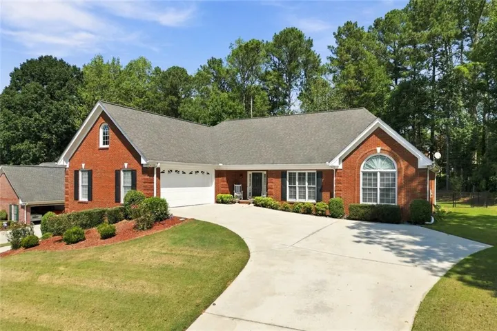 Four Sided Brick exterior with white trim, arched window, attached two-car garage, and a concrete driveway