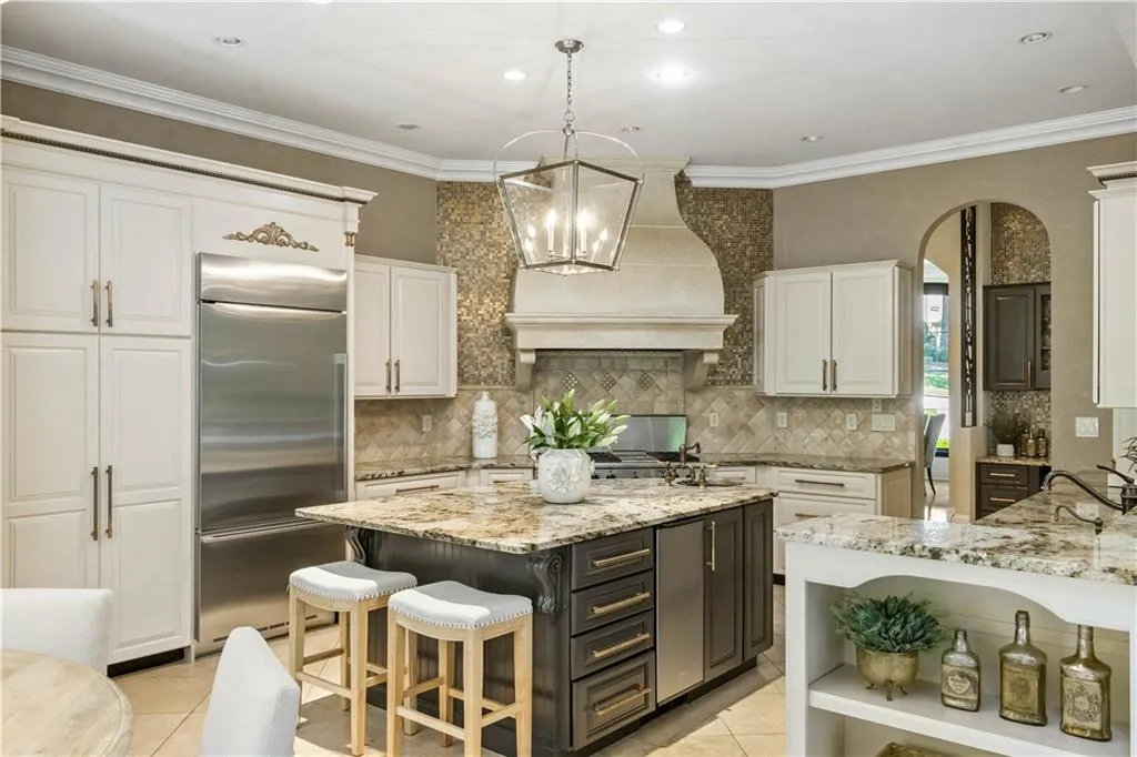 Kitchen featuring an island with sink, stainless steel built in refrigerator, white cabinets, and custom exhaust hood