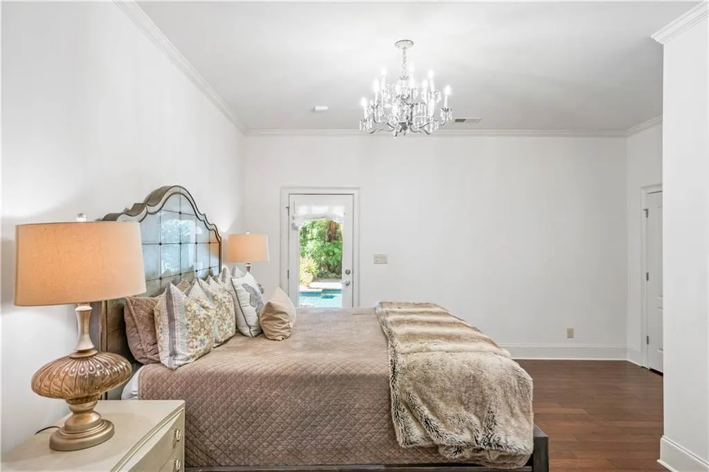 Bedroom featuring ornamental molding, access to exterior, a notable chandelier, and dark hardwood / wood-style floors