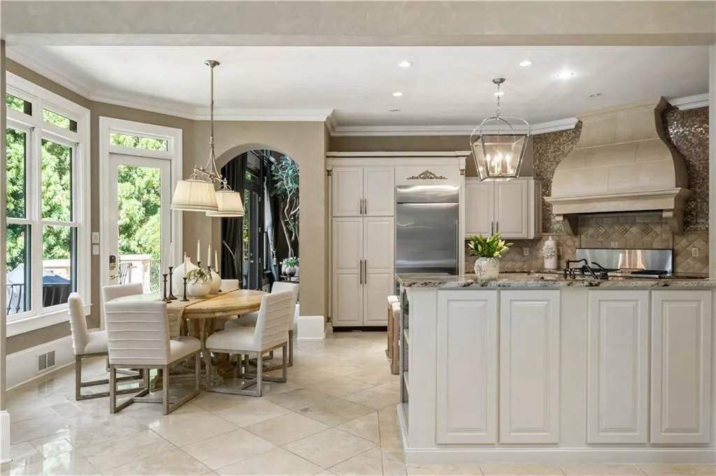 Kitchen with dark stone countertops, custom range hood, a chandelier, pendant lighting, and ornamental molding
