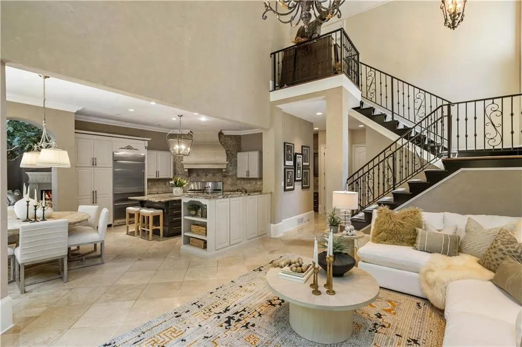 Living room with a towering ceiling, ornamental molding, light tile patterned floors, and a notable chandelier