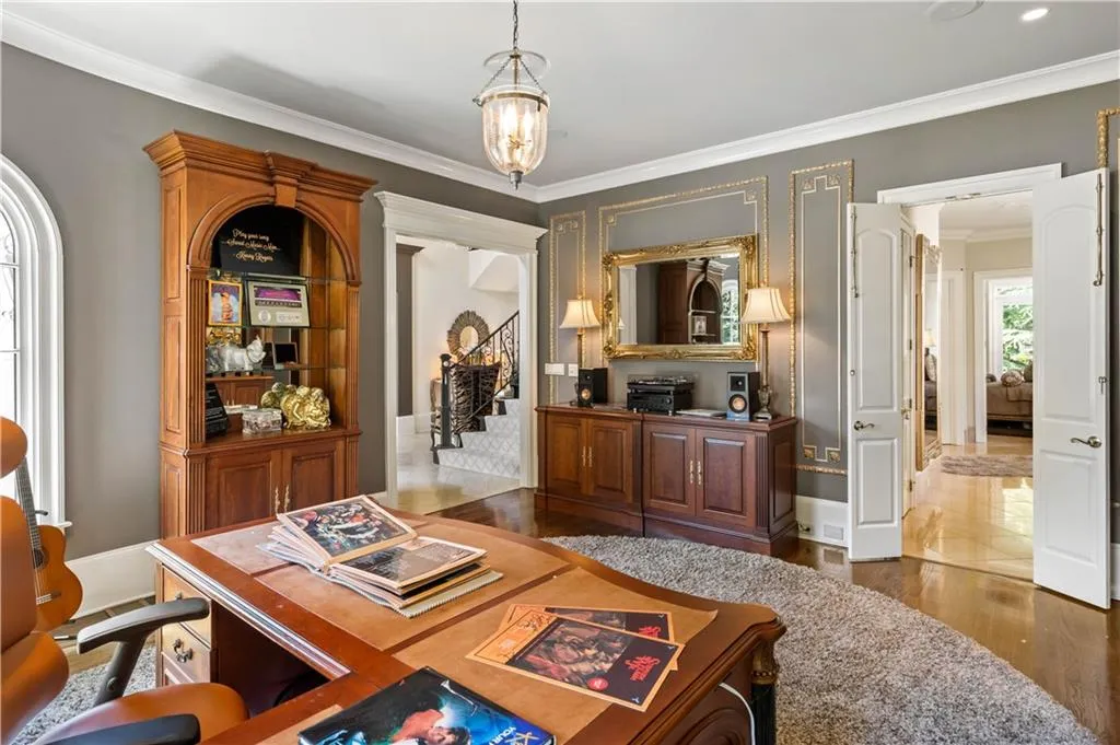Home office featuring dark wood-type flooring, ornamental molding, and a notable chandelier