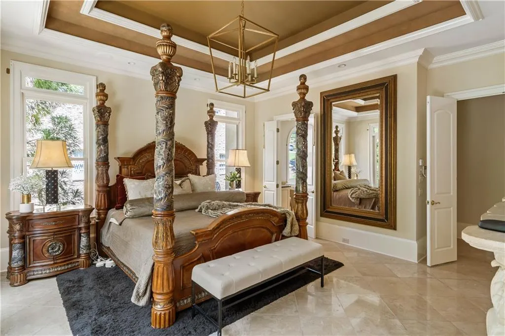 Tiled bedroom with ornamental molding, a raised ceiling, and a notable chandelier
