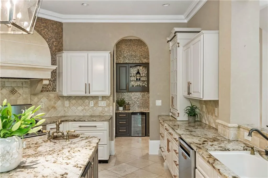 Kitchen featuring white cabinetry, sink, light tile patterned flooring, beverage cooler, and stainless steel dishwasher