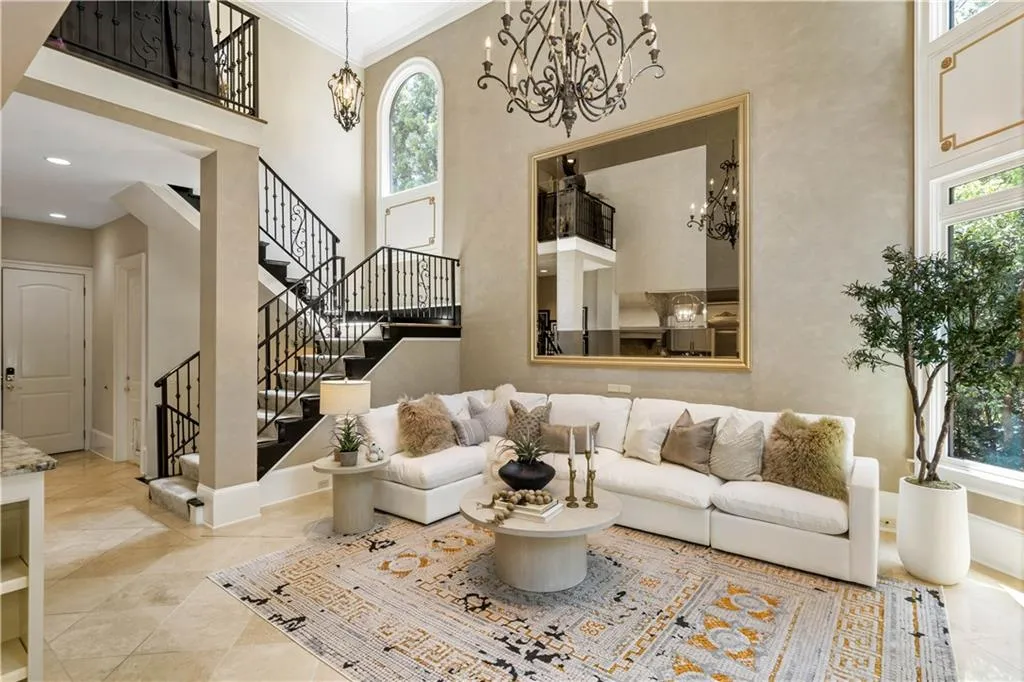 Living room with ornamental molding, a high ceiling, a notable chandelier, and light tile patterned floors