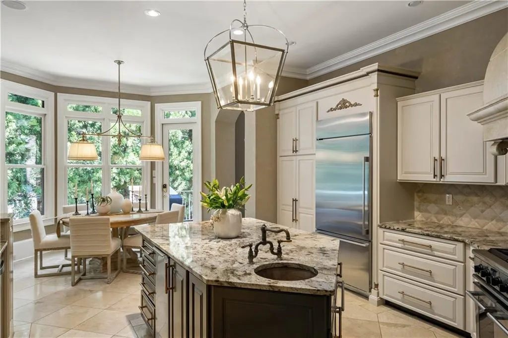 Kitchen with hanging light fixtures, premium appliances, a center island with sink, and a notable chandelier