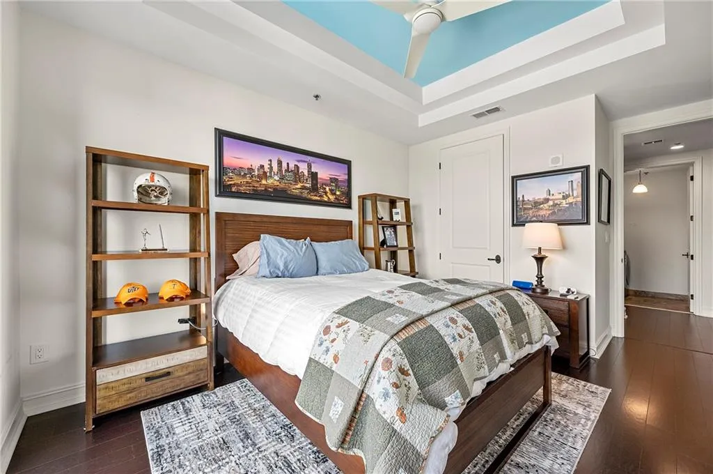 Bedroom with dark wood finished floors, a raised ceiling, visible vents, and baseboards