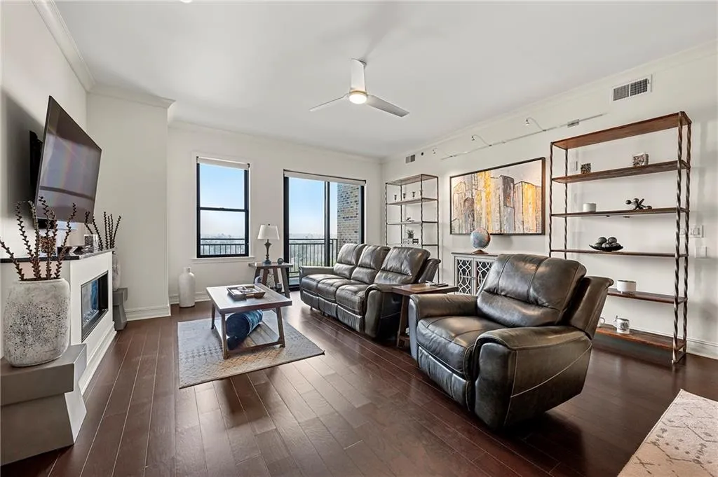 Living room with visible vents, dark wood flooring, crown molding, baseboards, and ceiling fan