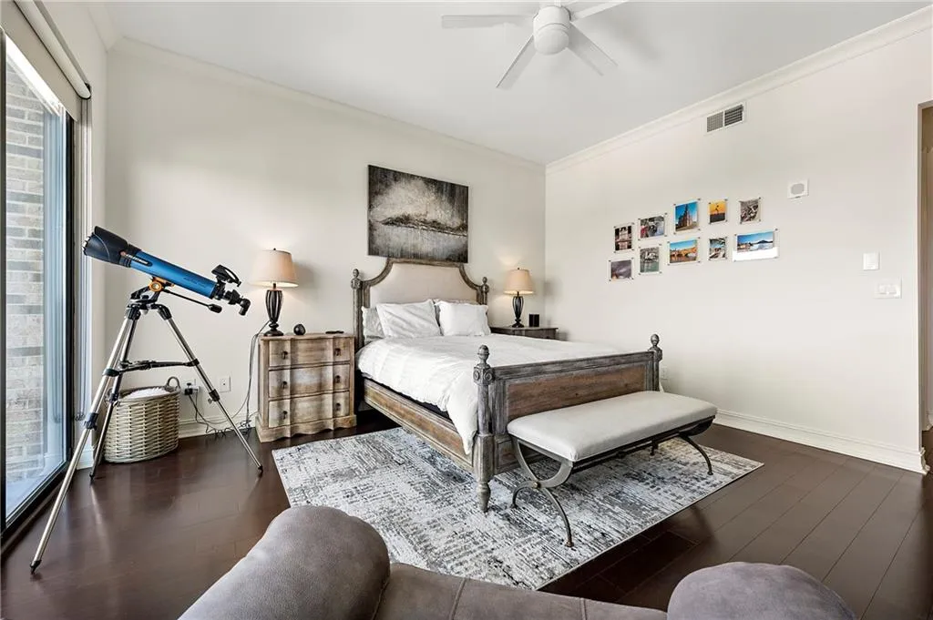 Primary Bedroom with a ceiling fan, wood finished floors, visible vents, baseboards, and crown molding