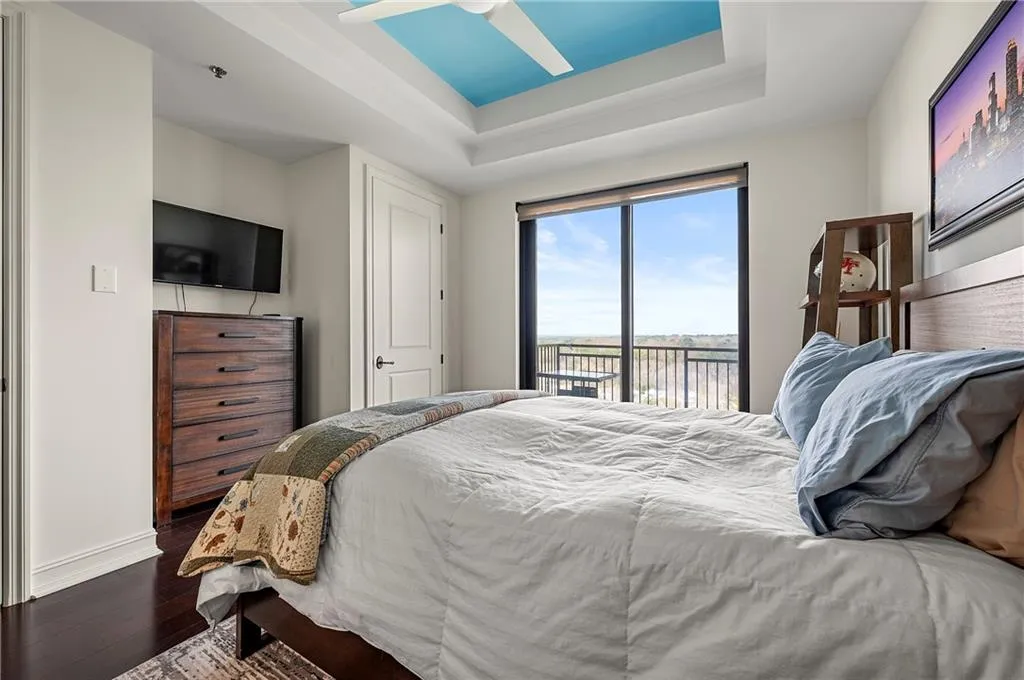 Bedroom with a raised ceiling, access to outside, baseboards, and dark wood flooring