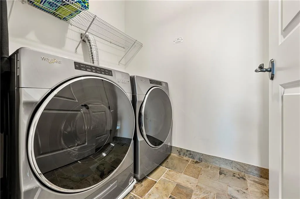 Laundry area with stone tile floors, laundry area, and washer and clothes dryer