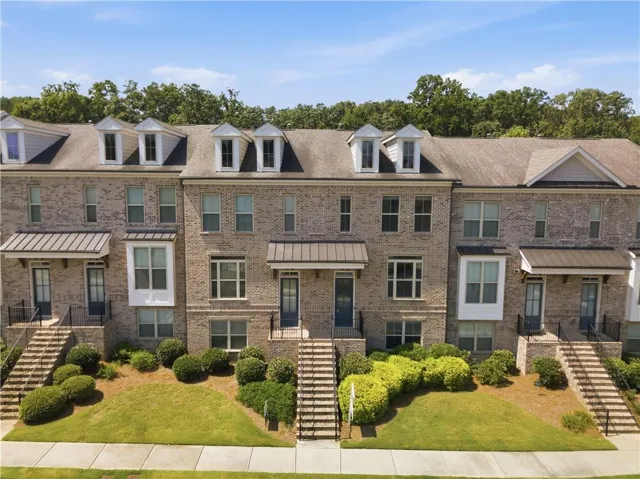 Brick townhome exterior featuring multiple dormer windows, a bay window, and gabled rooflines