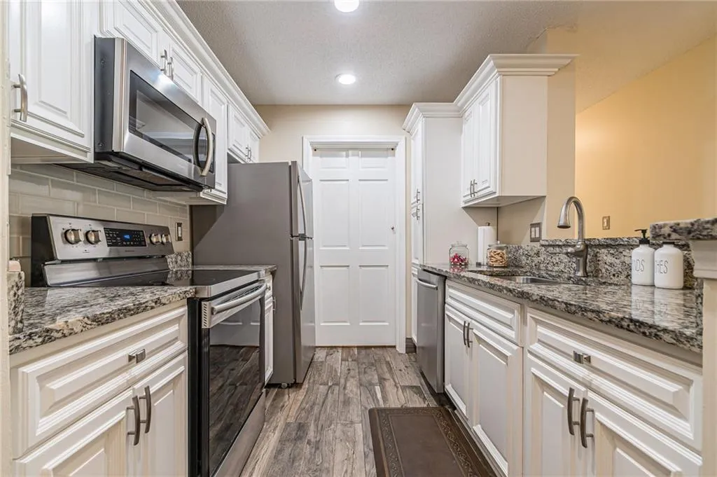Renovated Alley Kitchen with updated backsplash, granite countertops, white cabinets, and appliances with stainless steel finishes.