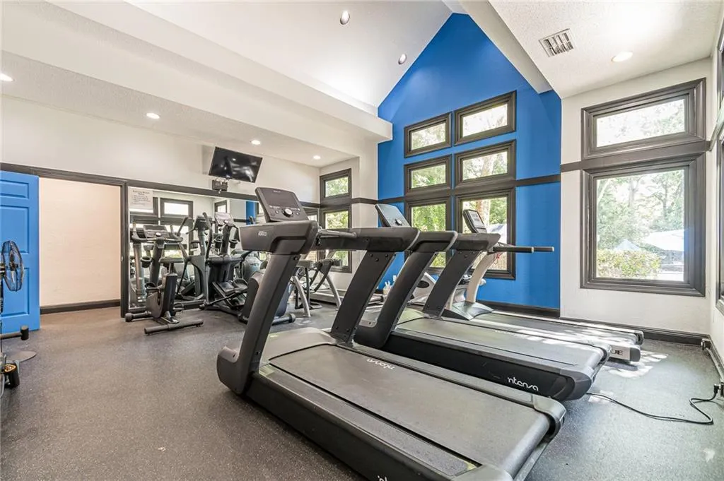 Gym with a wealth of natural light, a towering ceiling, and ample workout space.