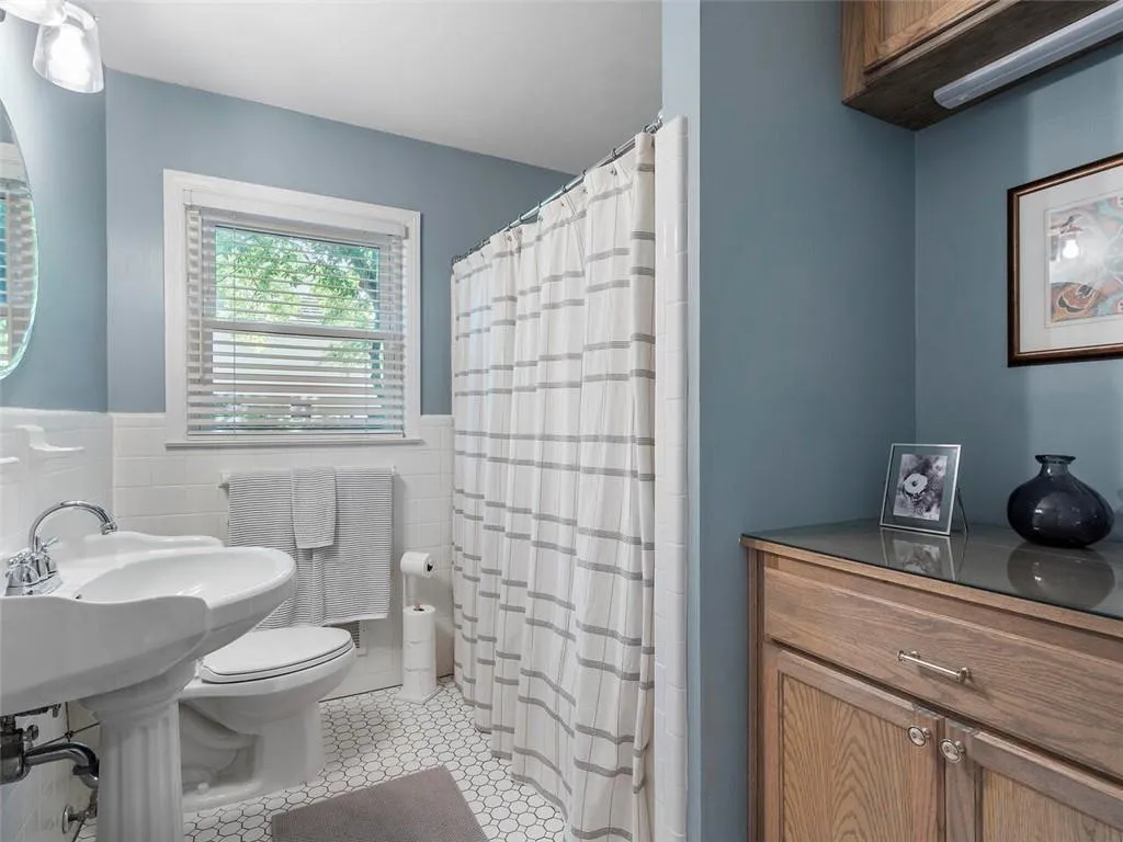 Bathroom with tile flooring, toilet, and tile walls