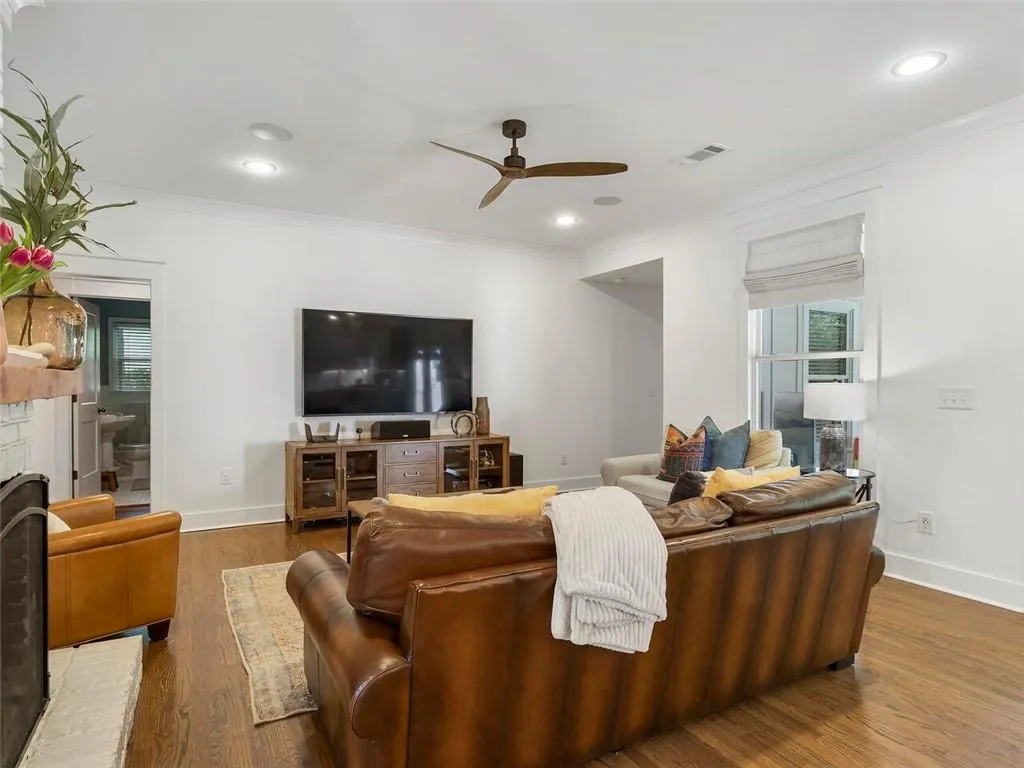 Living room featuring a brick fireplace, ceiling fan, crown molding, and wood-type flooring