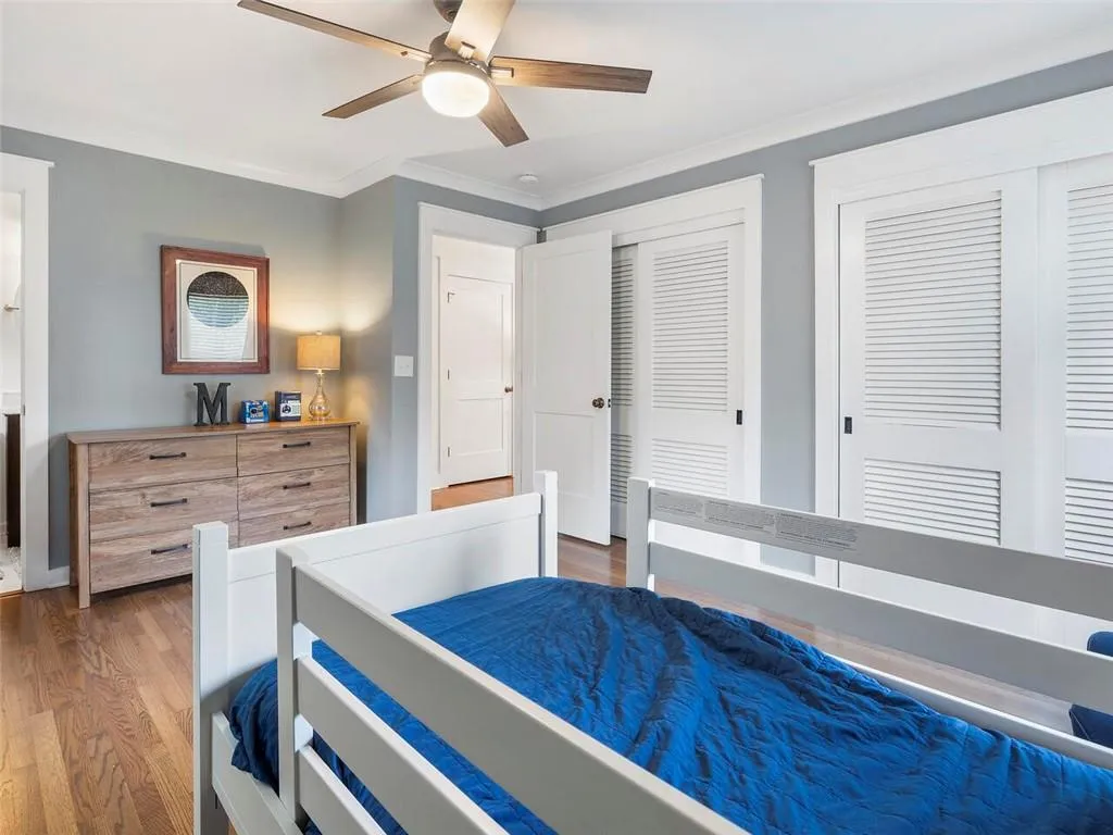 Bedroom with dark wood-type flooring, two closets, ceiling fan, and crown molding
