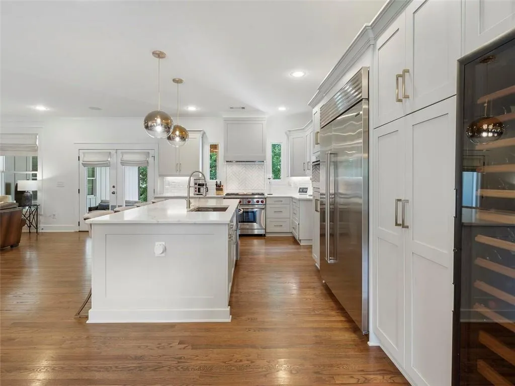 Kitchen featuring high end appliances, sink, hardwood / wood-style flooring, and backsplash