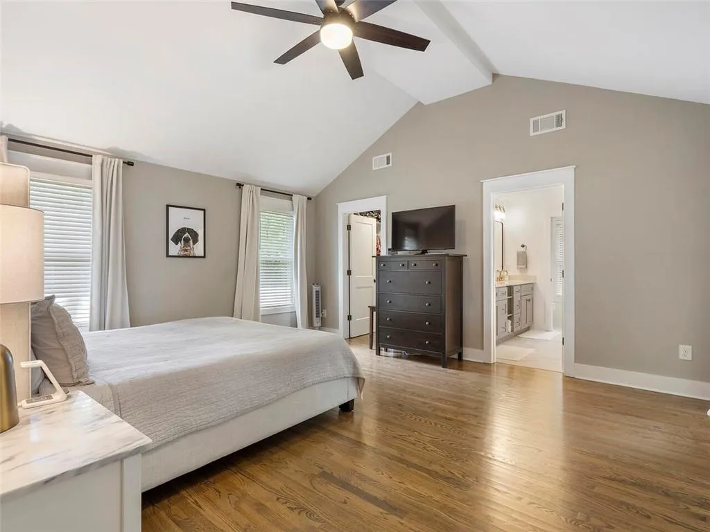 Bedroom with high vaulted ceiling, ensuite bathroom, ceiling fan, and hardwood / wood-style floors