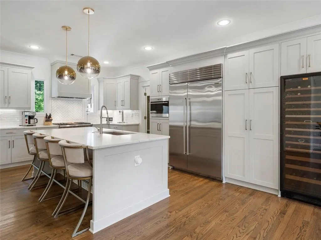 Kitchen with appliances with stainless steel finishes, hardwood / wood-style flooring, backsplash, wine cooler, and sink