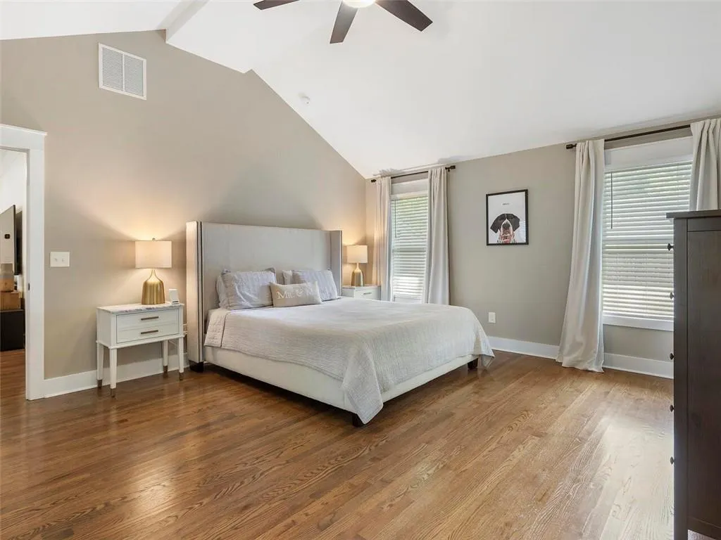 Bedroom with high vaulted ceiling, wood-type flooring, ceiling fan, and multiple windows