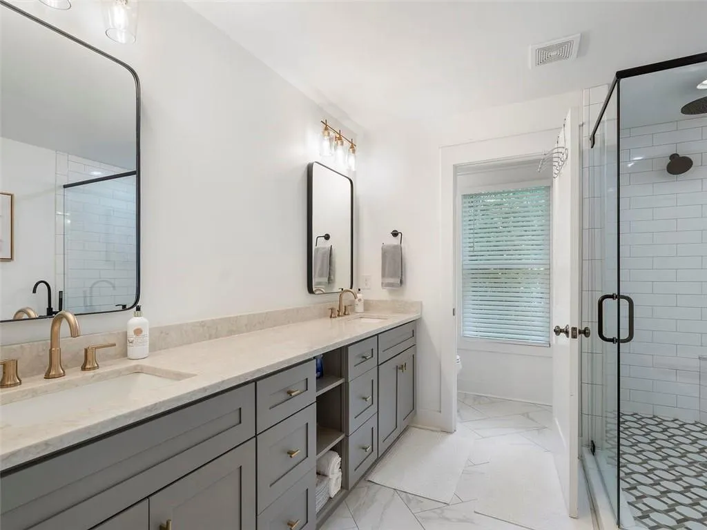 Bathroom with a shower with shower door, tile flooring, toilet, and large vanity