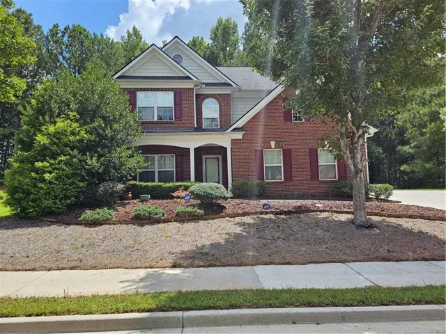 Brick exterior with white columned front porch and complementing red shutters