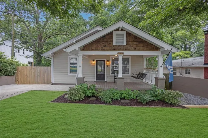 Craftsman-style home featuring a covered front porch, wood-look shake siding, light-toned horizontal siding, a manicured lawn, and a paved driveway