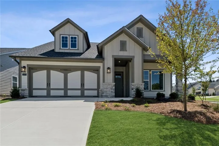 Modern farmhouse-style exterior with board and batten siding, stone accents, and a covered entry