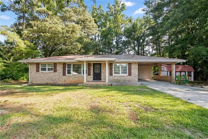 Single-story residence featuring a brick facade, covered front porch with white columns, and a brown metal roof