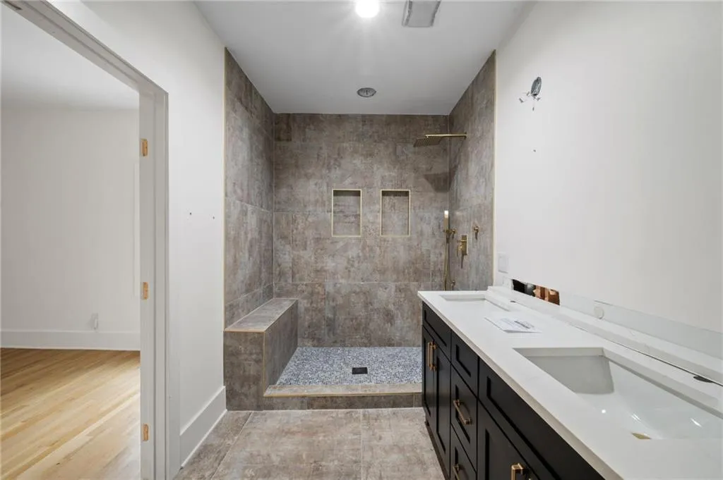 Bathroom with tiled shower, hardwood / wood-style floors, and vanity
