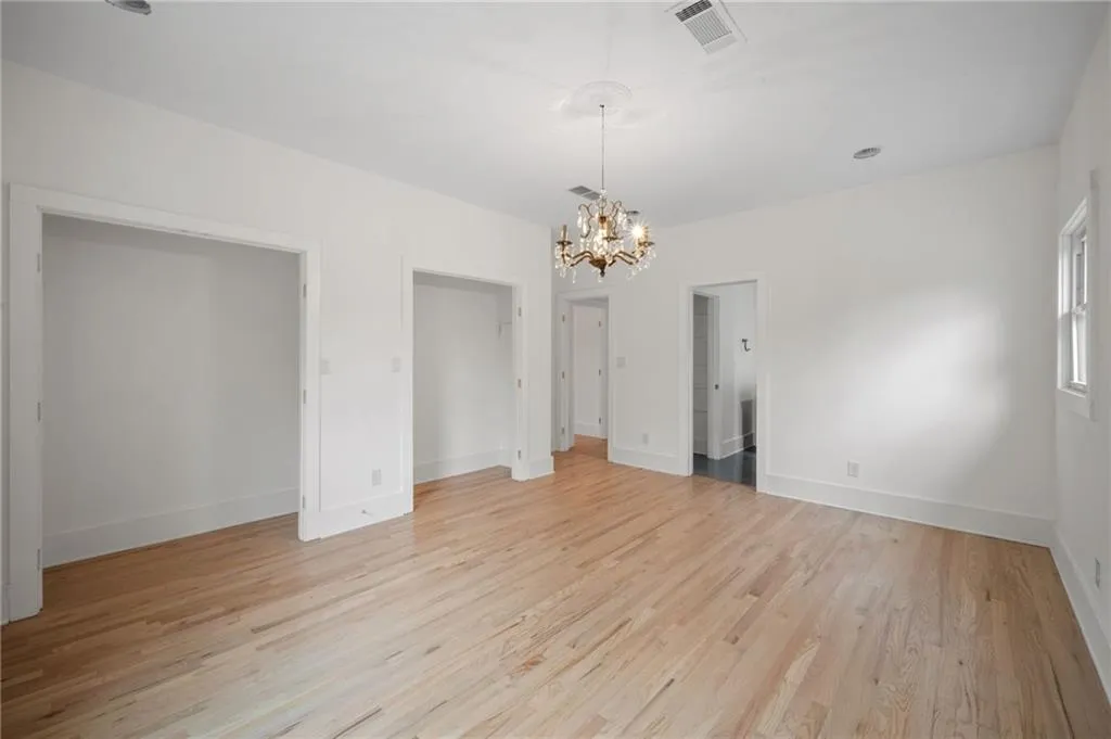 Unfurnished bedroom with a notable chandelier and light hardwood / wood-style floors