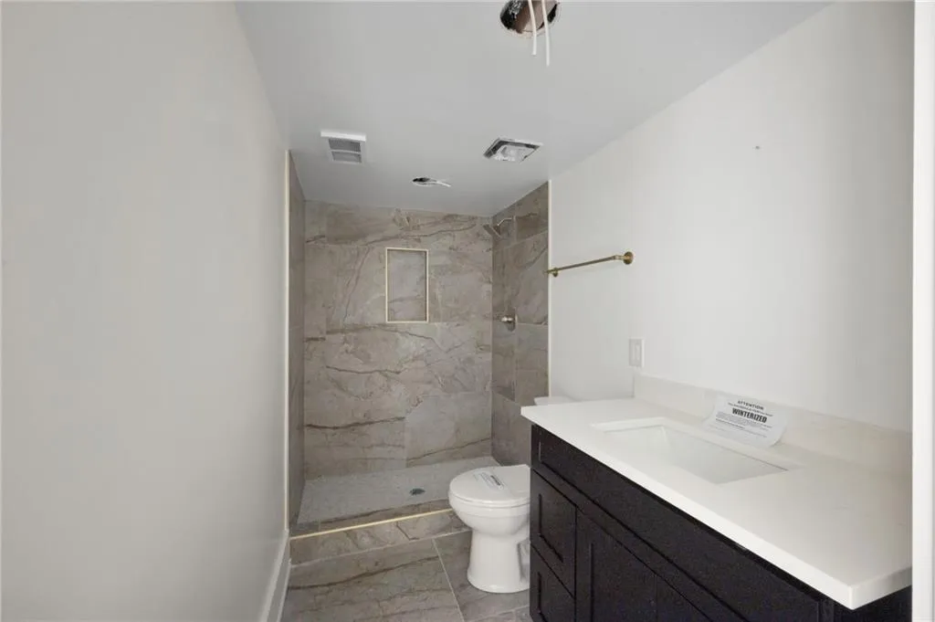Bathroom featuring vanity, toilet, and a tile shower