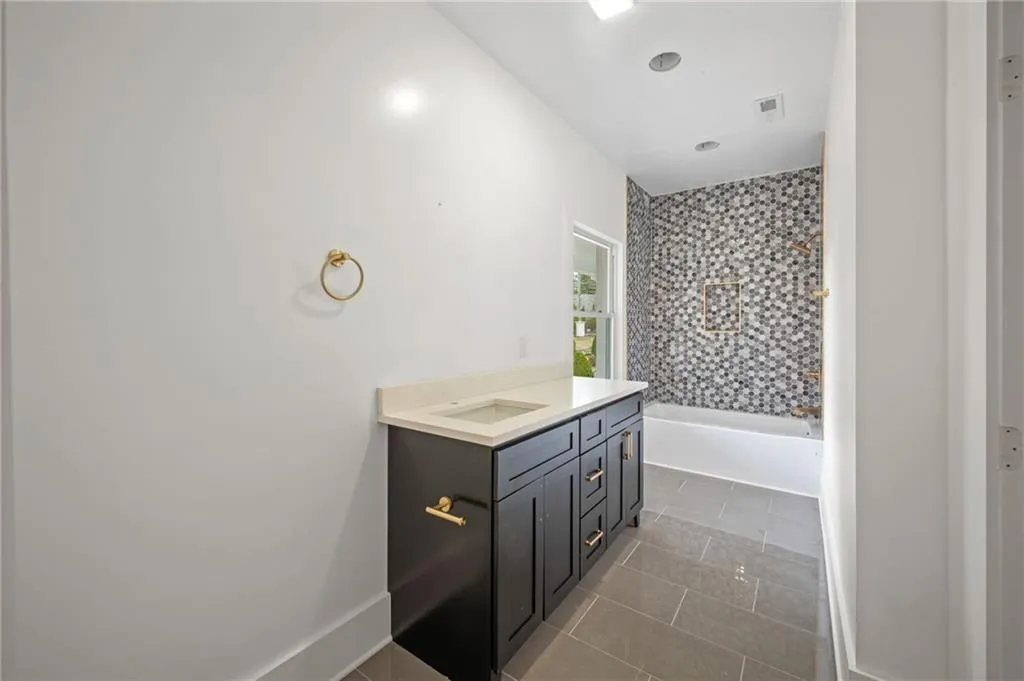 Bathroom with tile patterned flooring, vanity, and tiled shower / bath combo