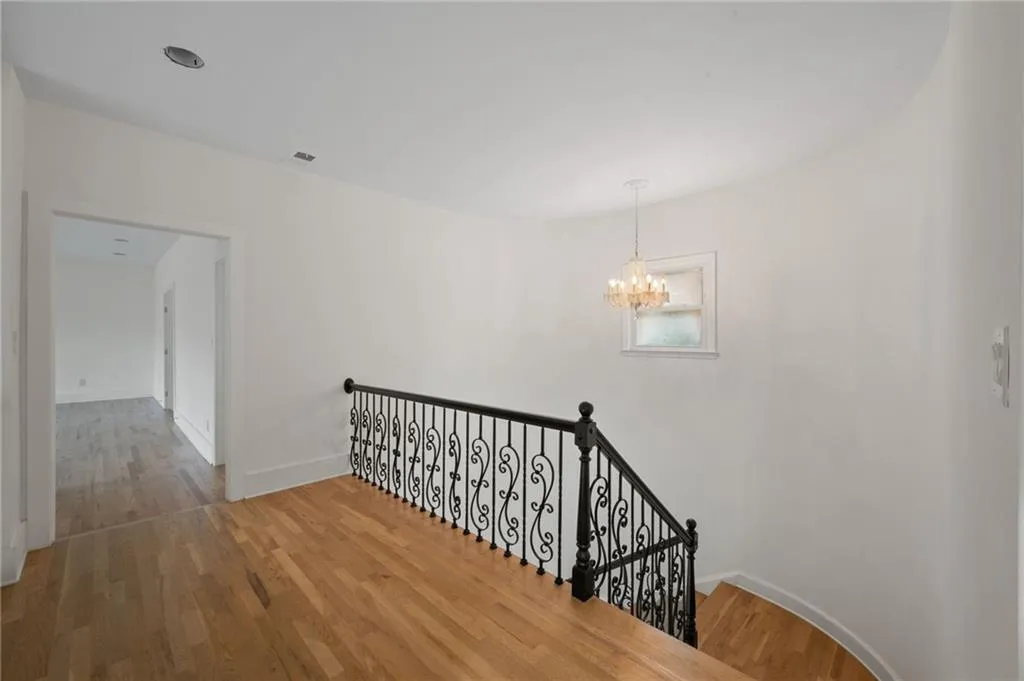 Stairway with hardwood / wood-style floors and a chandelier