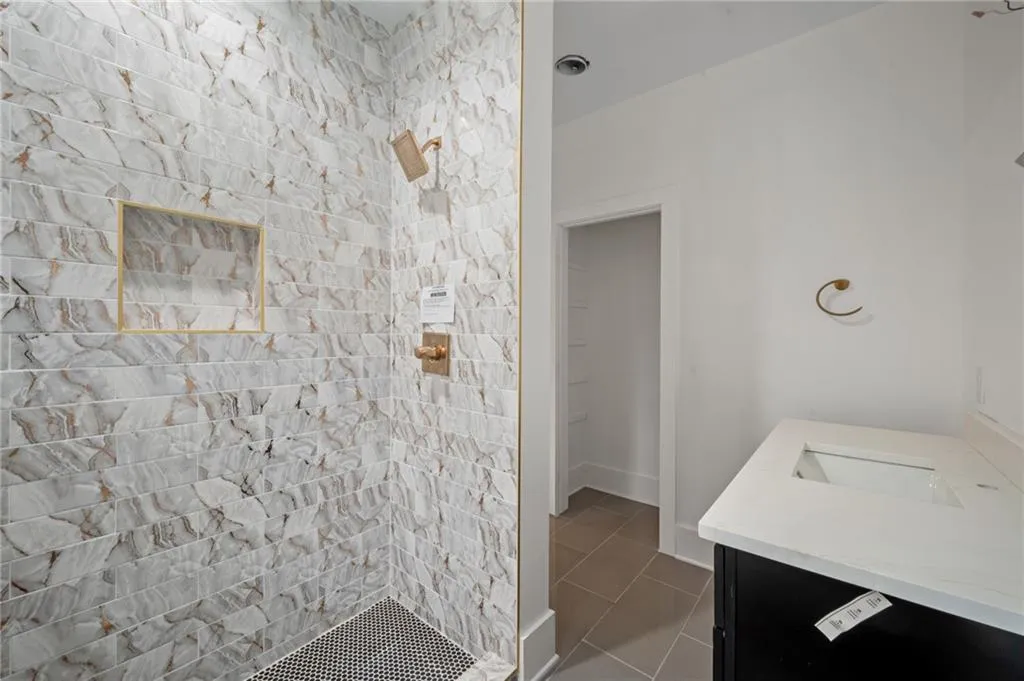 Bathroom with a tile shower, vanity, and tile patterned floors