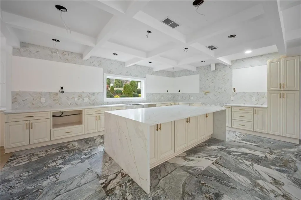 Kitchen featuring beam ceiling, coffered ceiling, tasteful backsplash, cream cabinets, and a kitchen island