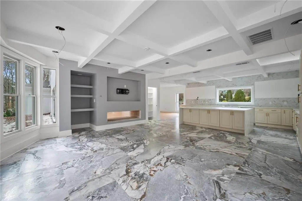 Unfurnished living room with beam ceiling, built in features, and plenty of natural light