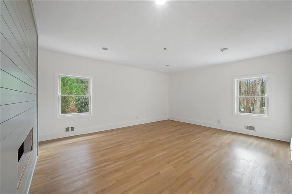 Unfurnished room featuring a healthy amount of sunlight, light wood-type flooring, and a fireplace