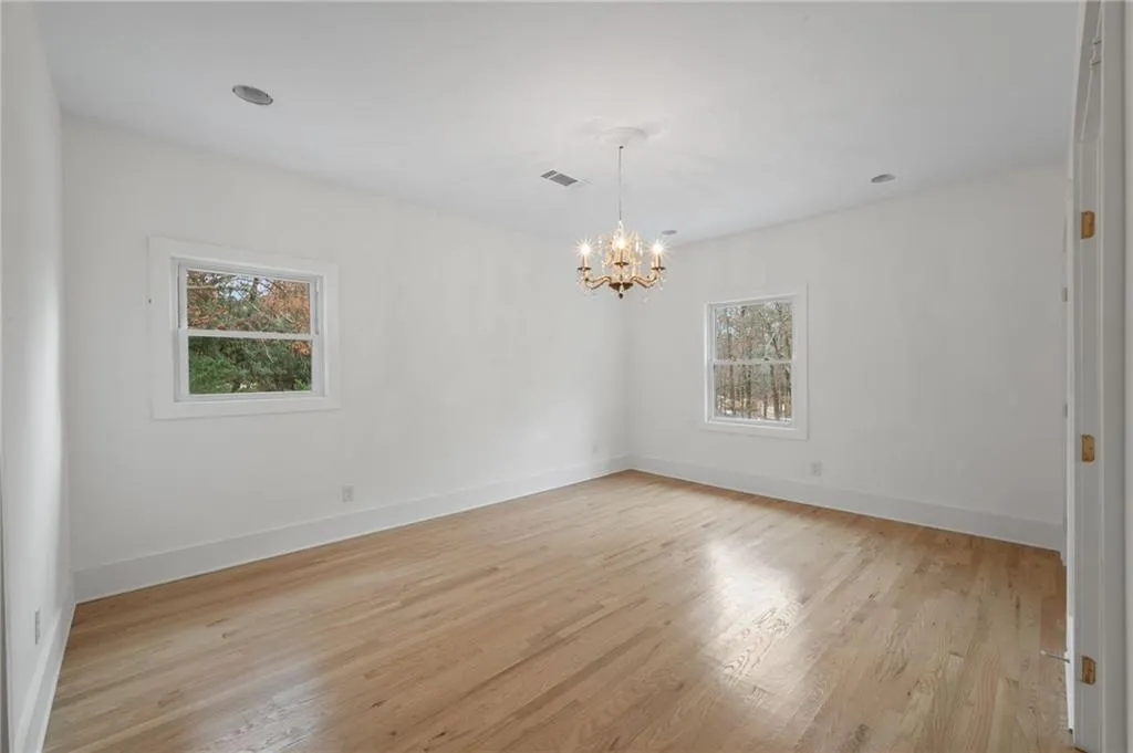 Spare room with a chandelier, a healthy amount of sunlight, and light hardwood / wood-style flooring